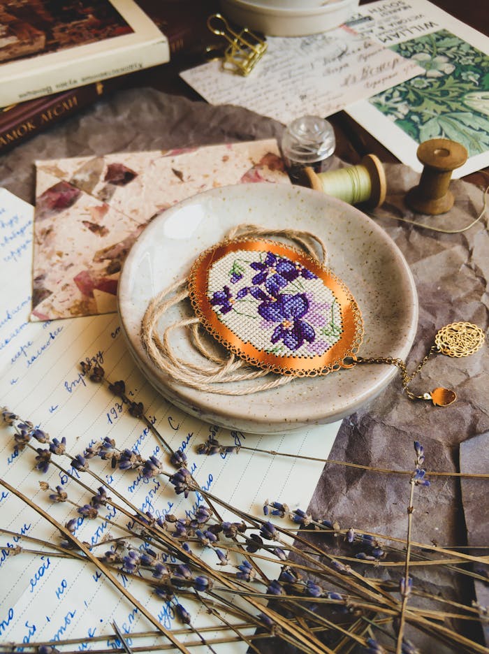 Artistic flat lay of embroidery with lavender and sewing thread on a rustic table.